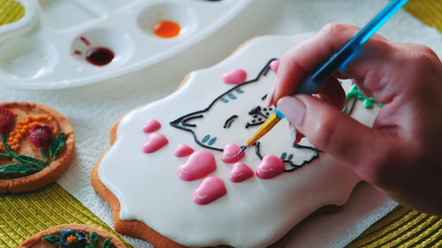 Cropped hand of woman painting on table