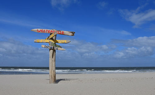 Information sign on beach against sky