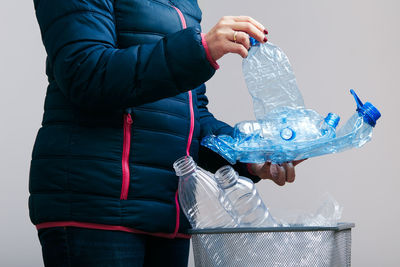 Midsection of woman throwing plastic bottles in bin