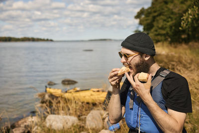 Man wearing life jacket eating at lake
