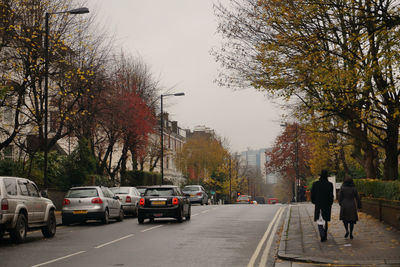 Rear view of people walking on road in autumn