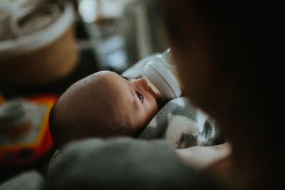 Close-up of mother feeding baby boy while sitting at home