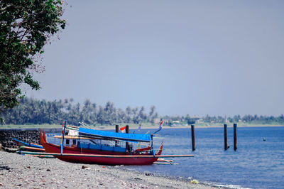 Boat moored on shore against clear sky