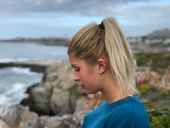 Side view of thoughtful young woman by sea