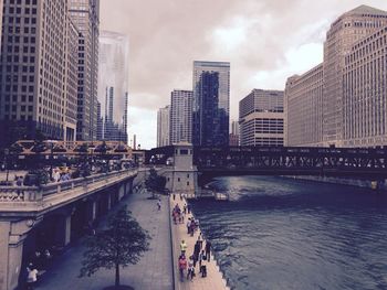 Bridge over river by buildings against sky in city