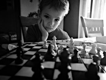 Boy with hand on chin looking at chess