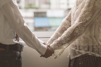 Midsection of woman and man holding hands