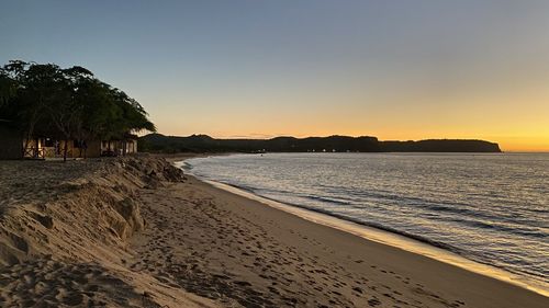 Scenic view of beach against clear sky during sunset