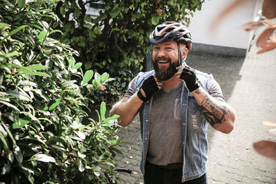 Portrait of laughing man putting on bicycle helmet