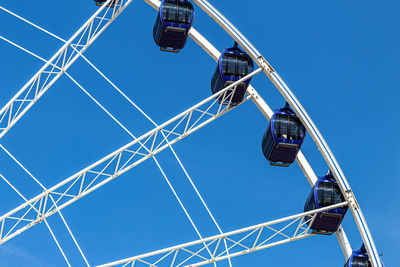 Low angle view of ferris wheel against clear blue sky