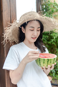 Portrait of woman wearing hat while standing against plants