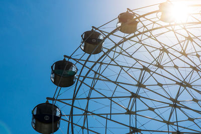 Low angle view of ferris wheel against clear blue sky on sunny day