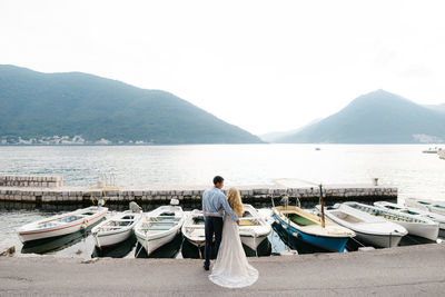 Rear view of man sitting on boat in lake against sky