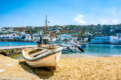 Boats moored at harbor by city against sky