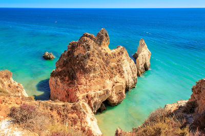 Rocks on sea shore against blue sky