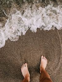 Low section of feet on sand at beach