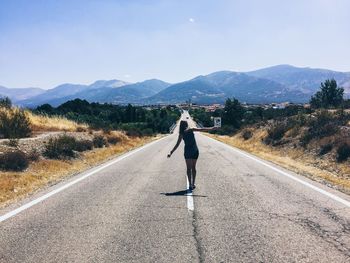 Rear view of woman walking on road against sky