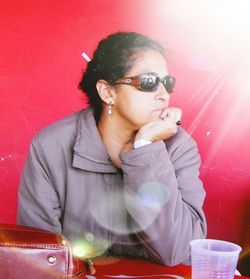 Woman sitting at cafe against red wall