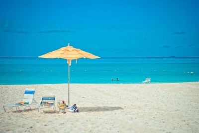 Deck chairs on beach against blue sky