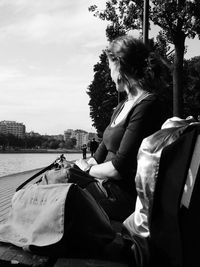 Side view of woman relaxing on bench in city