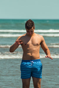 Full length of shirtless man standing on beach