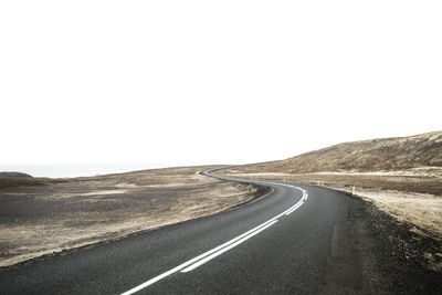 Road passing through landscape against clear sky