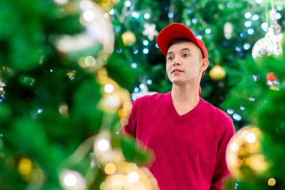 Portrait of man standing against illuminated christmas tree