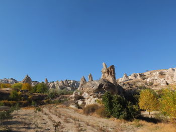 Rock formations on landscape against clear blue sky