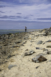 Rear view of man on beach against sky