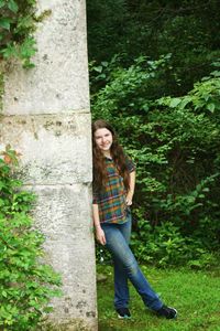 Portrait of young woman standing against tree