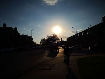 Cars on city street against sky during sunset