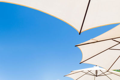 Low angle view of parasol against clear blue sky