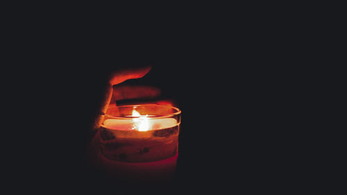 Close-up of lit candle in darkroom