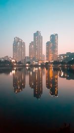 Reflection of illuminated buildings in city against sky