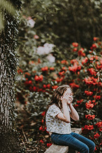 Woman standing by tree trunk