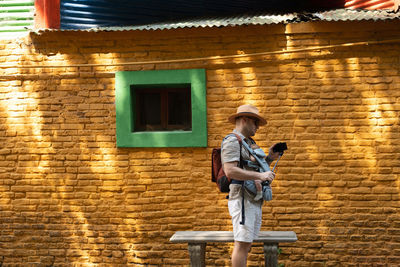 Side view of man standing against wall with beautiful shadows with newborn baby. travel concept.