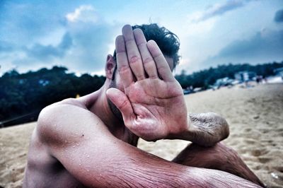 Close-up of cropped hand holding object against sky