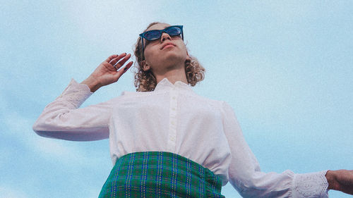 Low angle view of man wearing sunglasses standing against sky