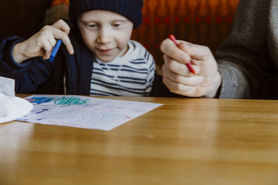 Father and son colouring in restaurant booth waiting for food