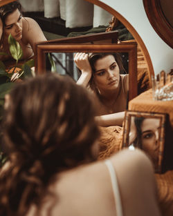 Beautiful young woman lying infront of different mirrors.