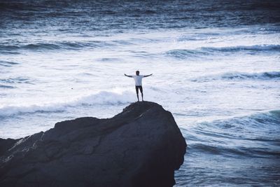 Rear view of man standing on beach against sky