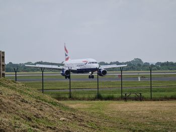 Airplane on airport runway against sky