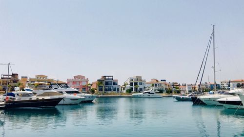 Boats moored at harbor against clear sky