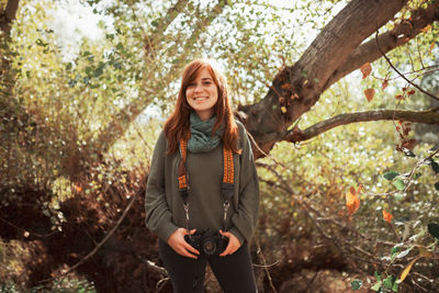 Portrait of smiling young woman standing in forest