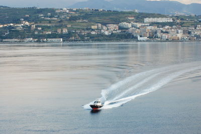 Boat sailing on sea by city