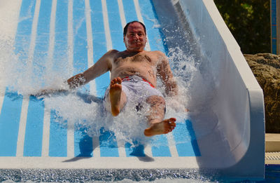 Portrait of man on water slide at amusement park