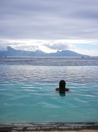 Rear view of man swimming in lake against sky