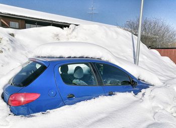 Snow covered car against blue sky