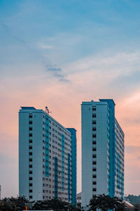 Modern buildings in city against sky during sunset