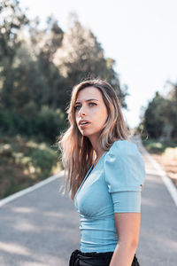 Beautiful woman standing on road against trees